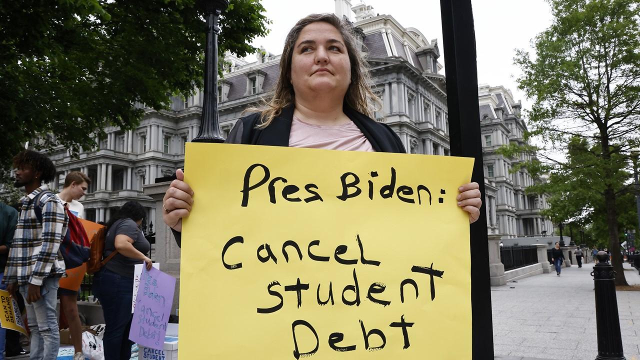 Woman holding a sign about canceling student debt