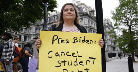 Woman holding a sign about canceling student debt