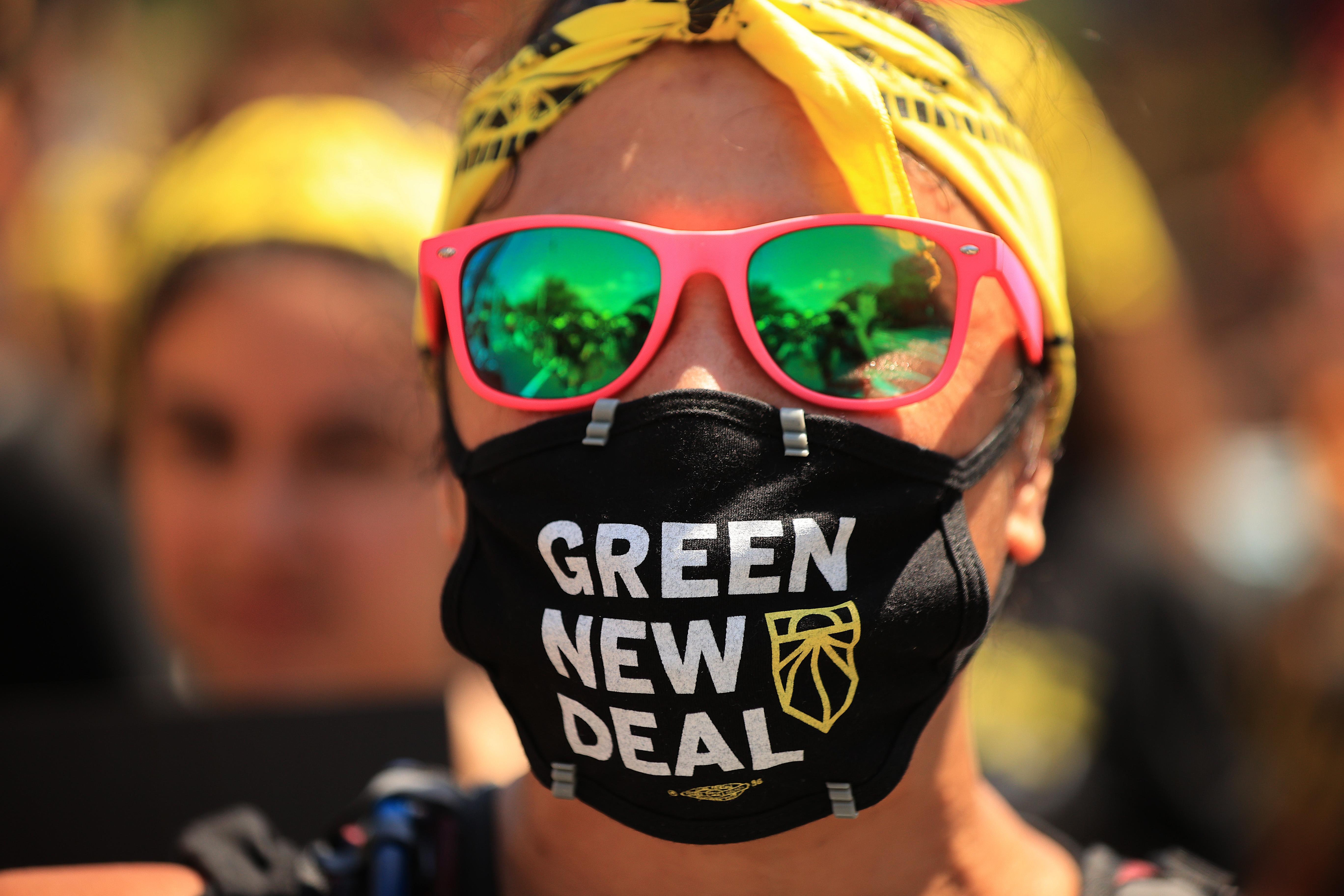 Woman wearing sunglasses and face mask that says Green New Deal