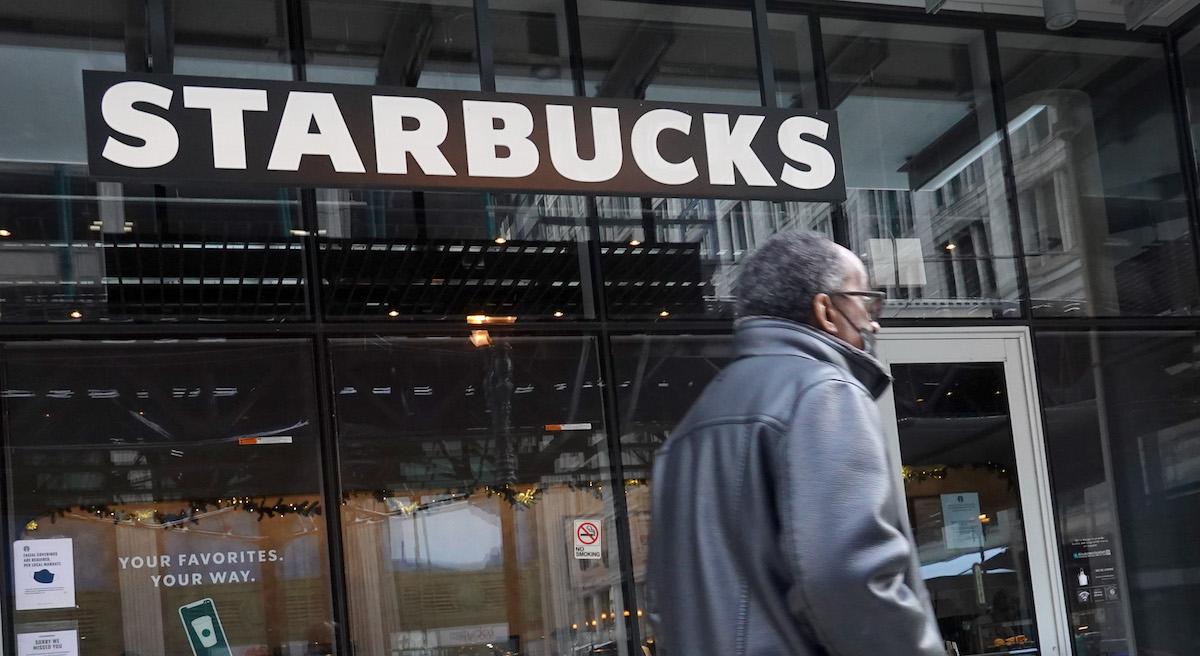 A man walking in front of a Starbucks