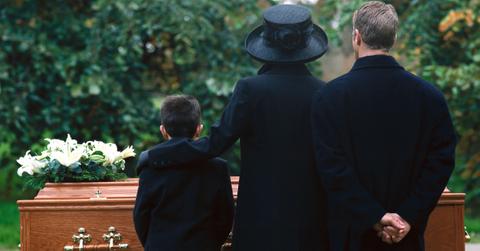 A family dressed in black gathers for a funeral.
