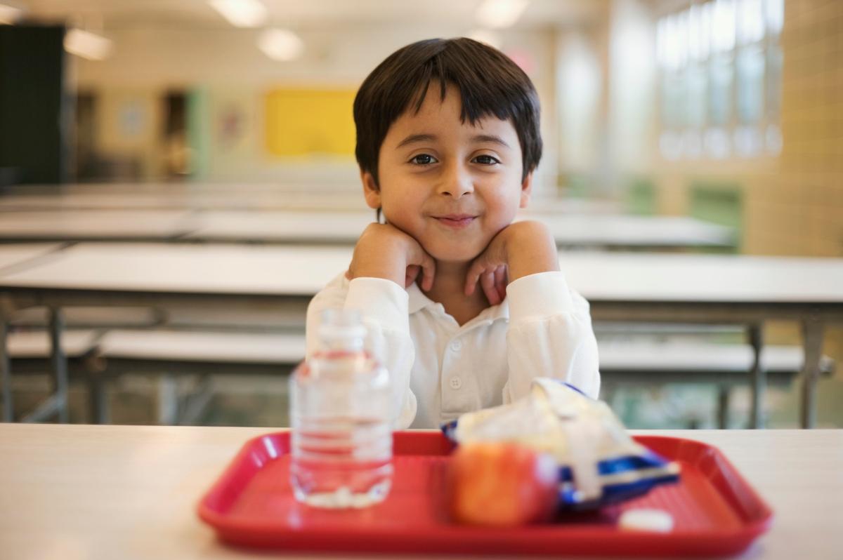 Child sitting at a table with a school lunch