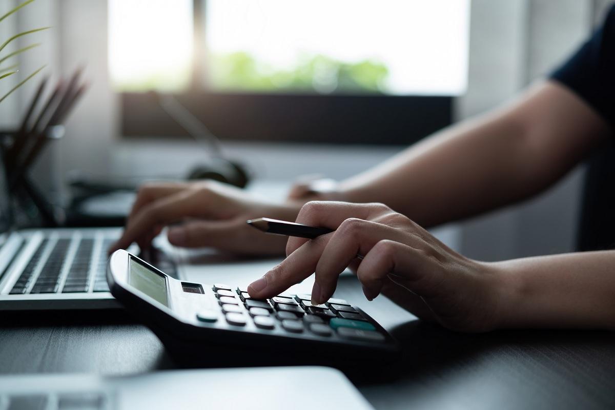 A person using a calculator and computer