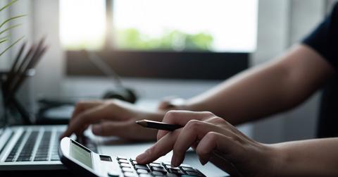 A person using a calculator and computer