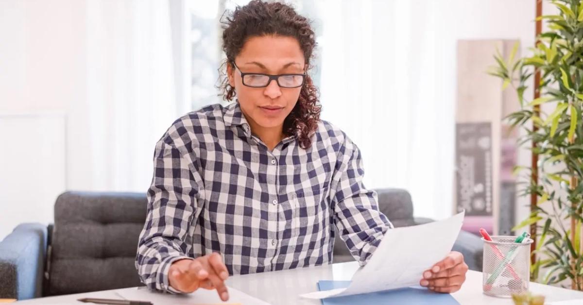 A tax preparer in a plaid shirt calculates taxes at desk.