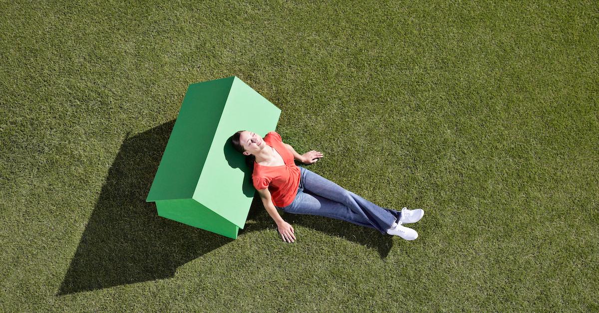 A person resting on a miniature green house 