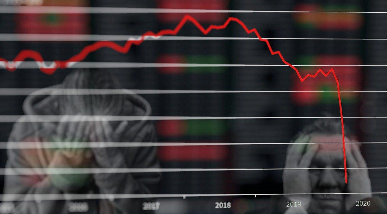 A chart depicting an economic crash and people holding their heads in despair