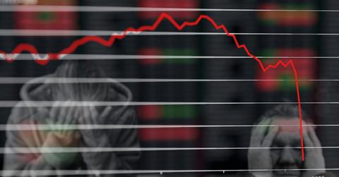 A chart depicting an economic crash and people holding their heads in despair