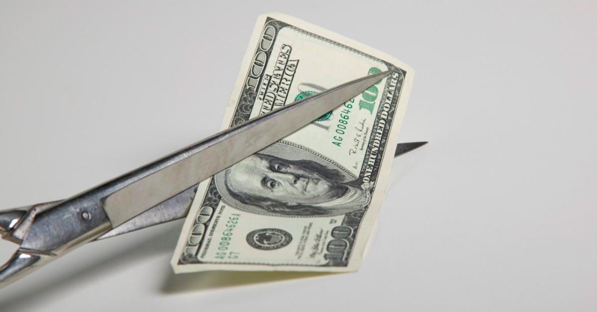 Scissors cutting $100 bill