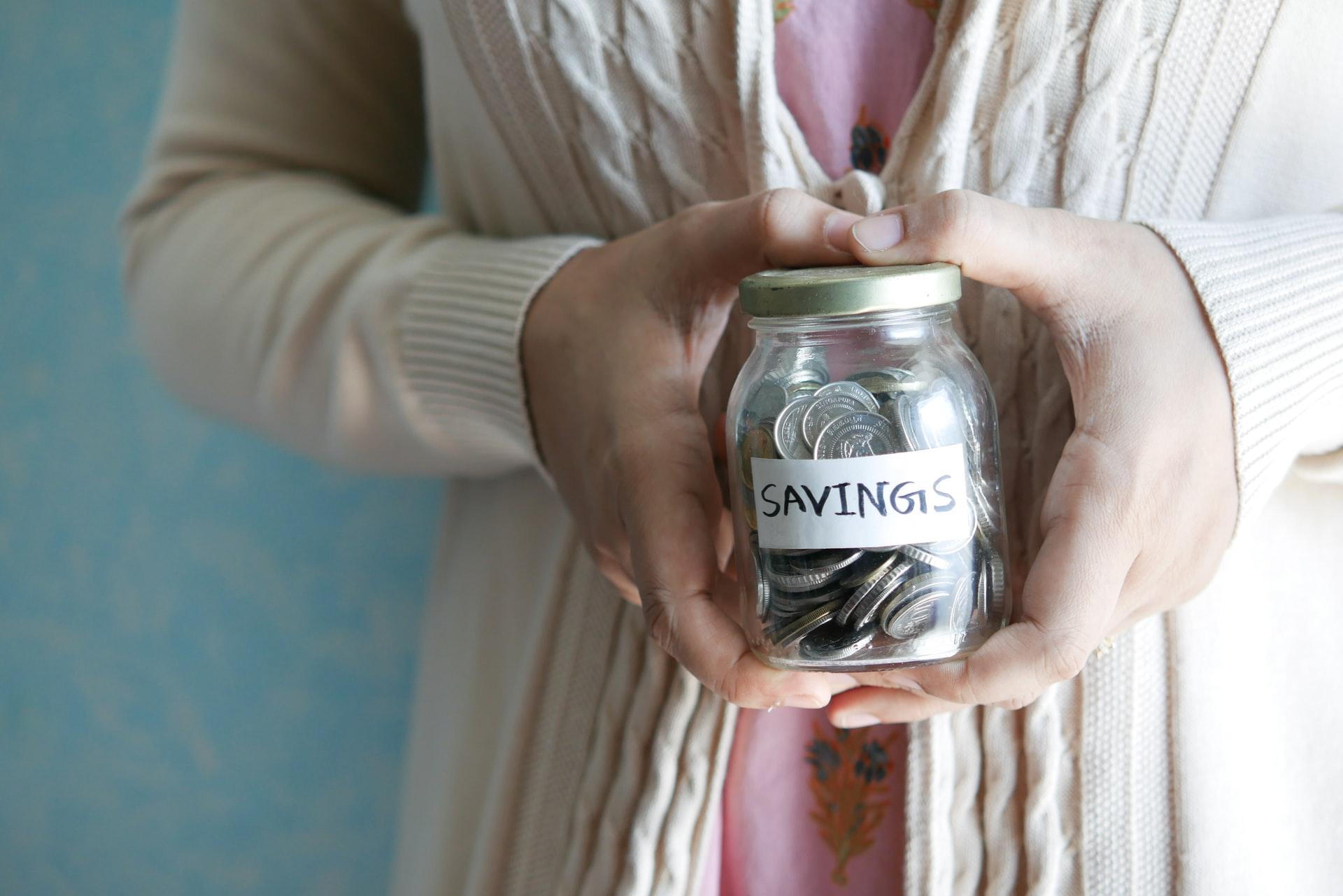 A person holding a jar with coins