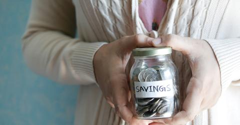 A person holding a jar with coins