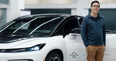 A person posing with a Faraday Future electric vehicle