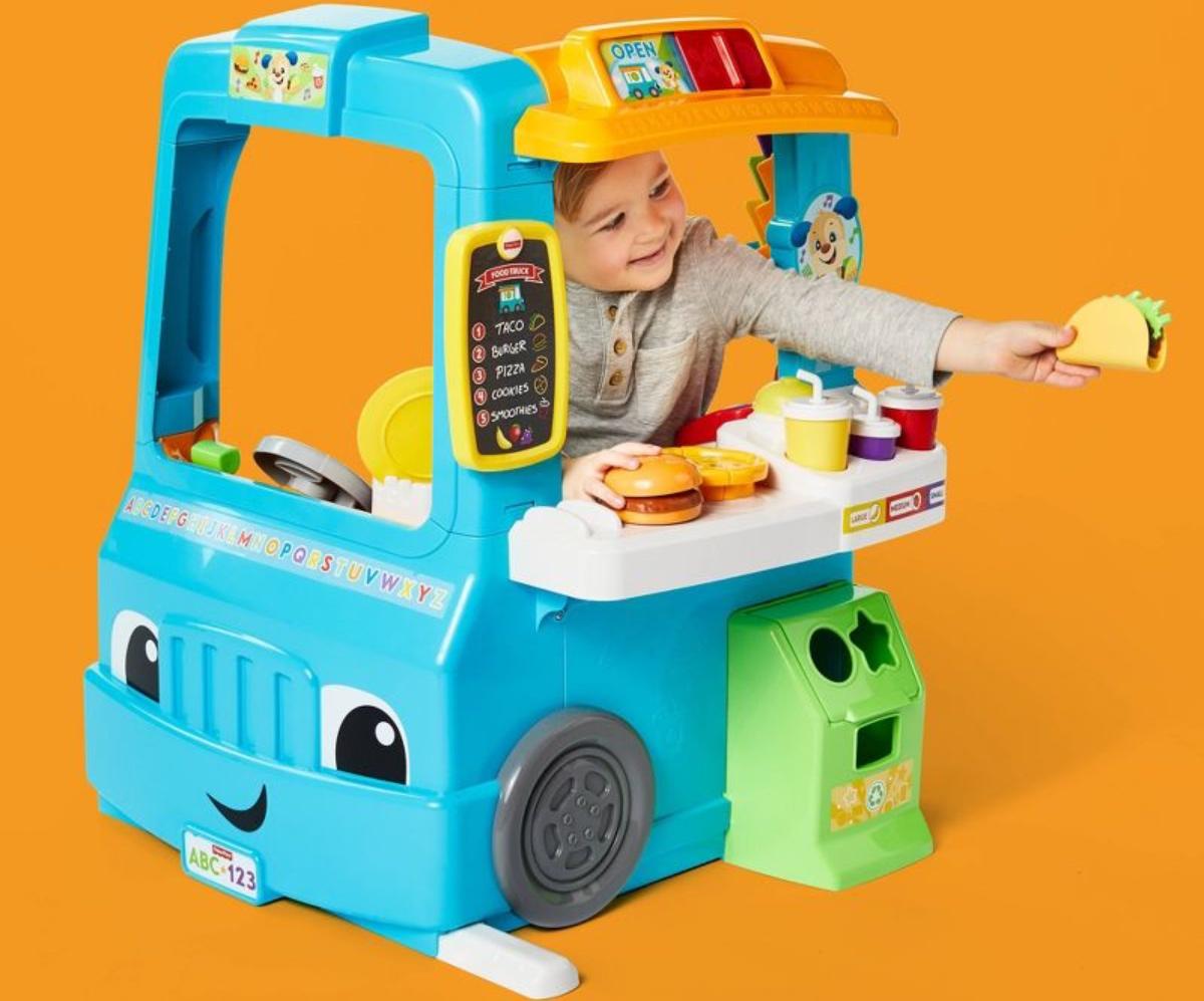 A young child playing with a toy food truck