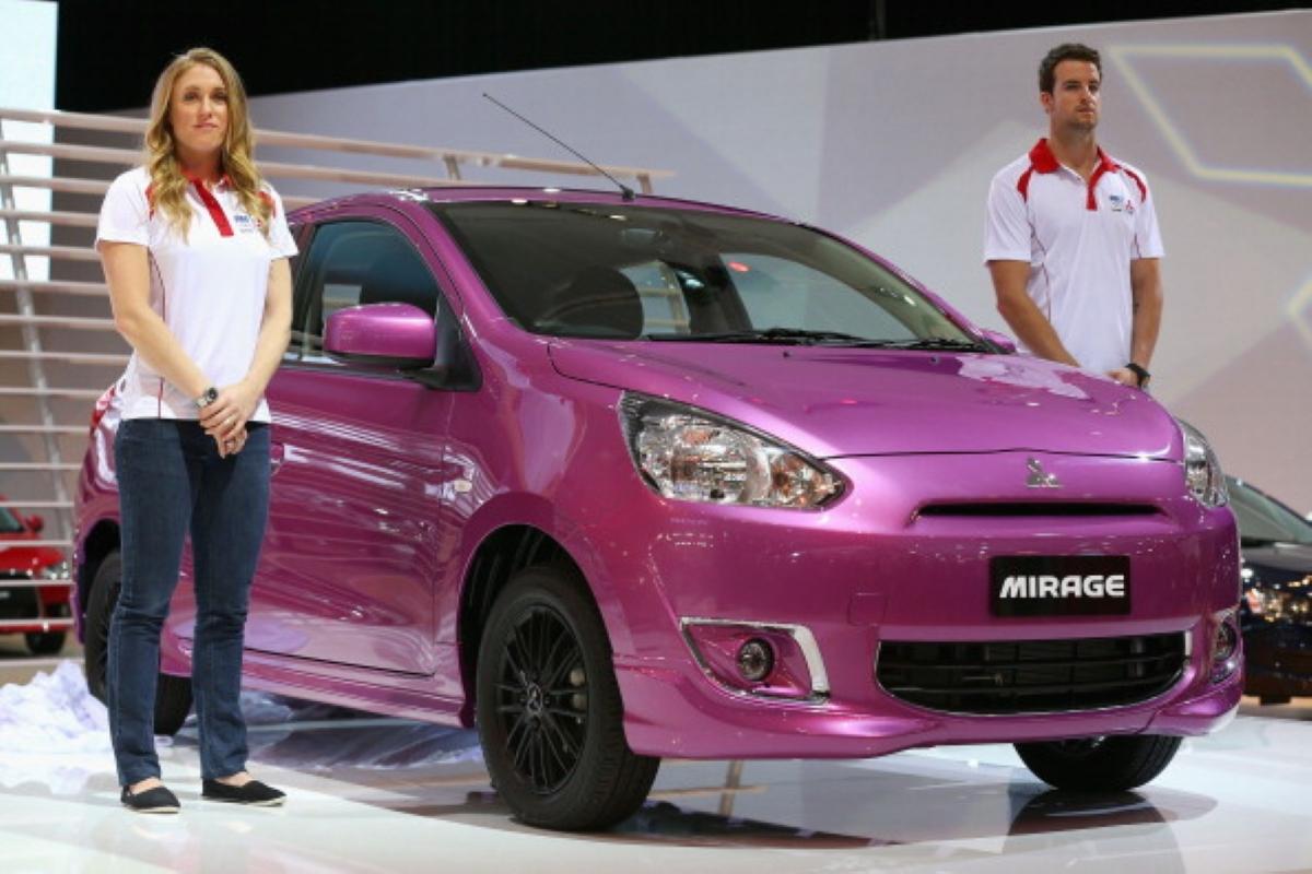 people standing next to a mitsubishi mirage