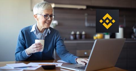 Woman looking on a laptop and Binance logo