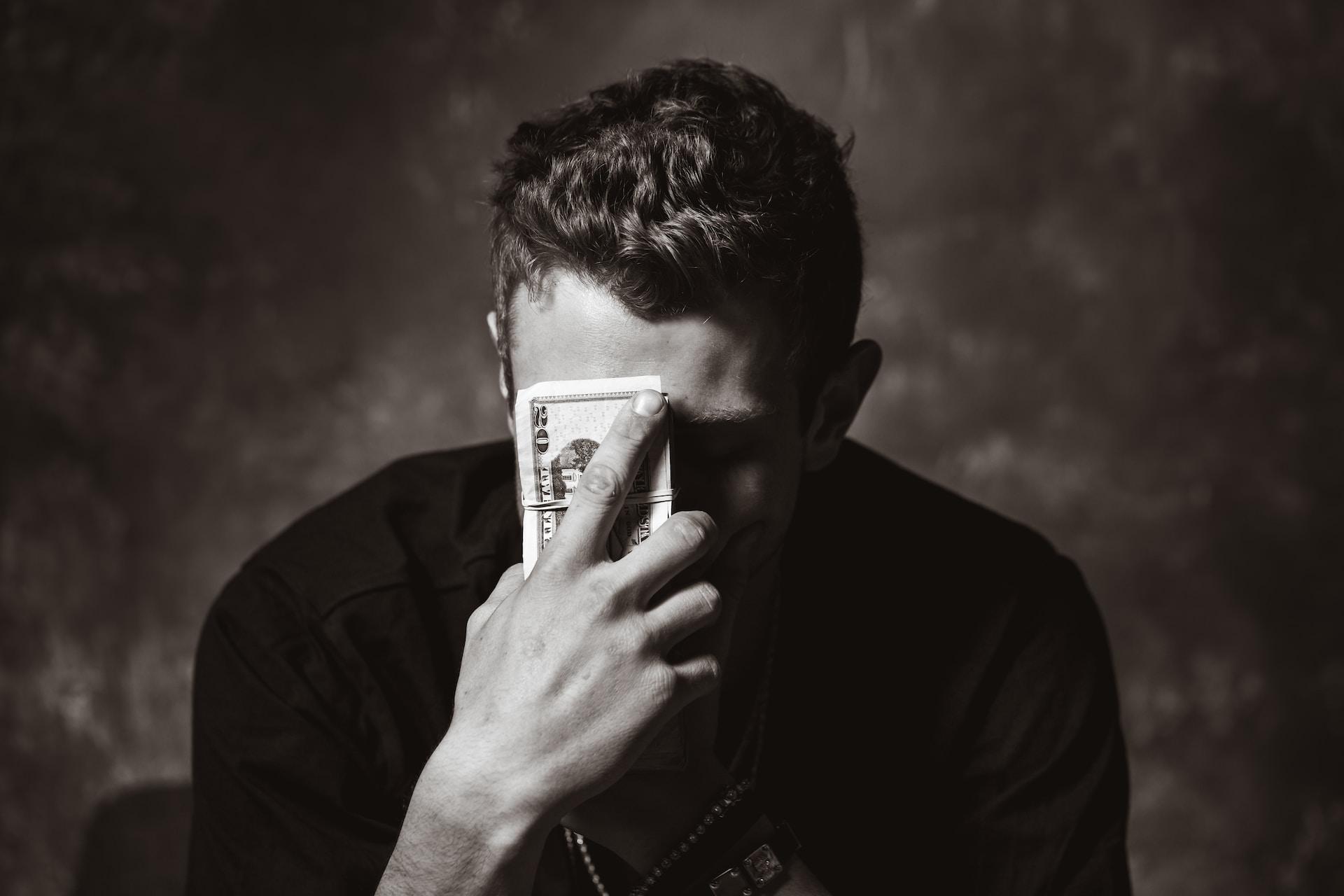 A black-and-white picture of a man holding a banknote 