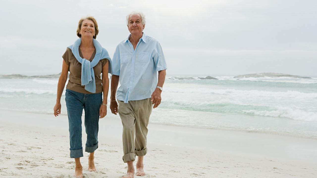 A retired couple walking on the beach