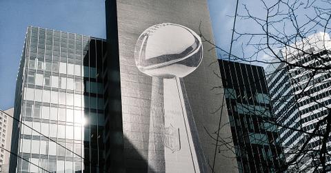 A large graphic of the Vince Lombardi Trophy promoting Super Bowl 50 is displayed on a skyscraper
