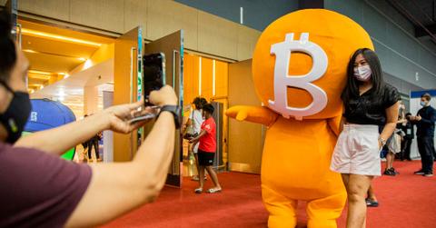 Bitcoin mascot posing with person wearing a mask