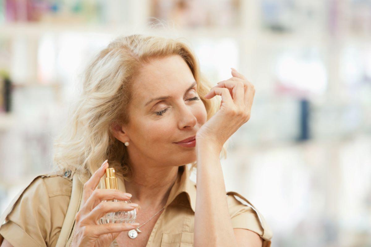 Woman with perfume bottle in hand sniffing her wrist