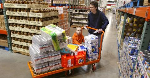 A man and his child shop for bulk items with large cart.