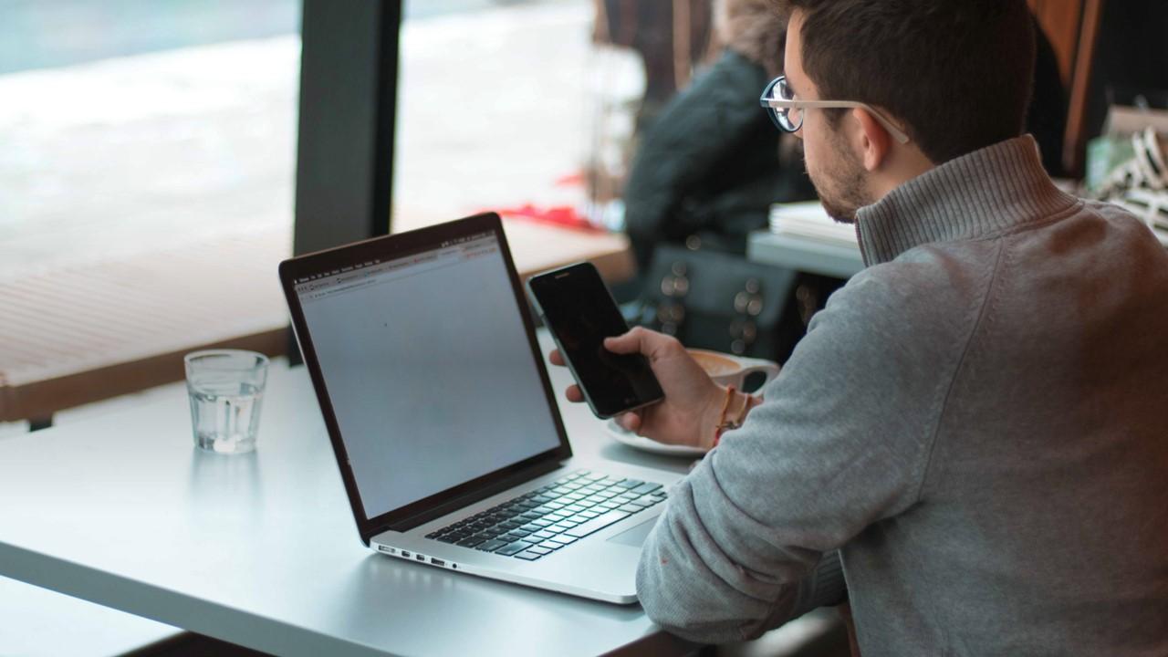 Person on computer and phone at cafe