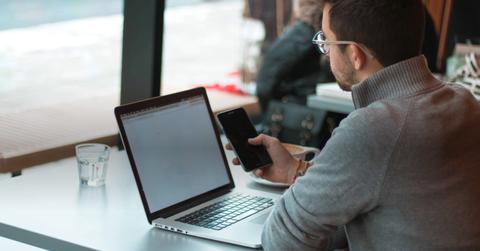 Person on computer and phone at cafe