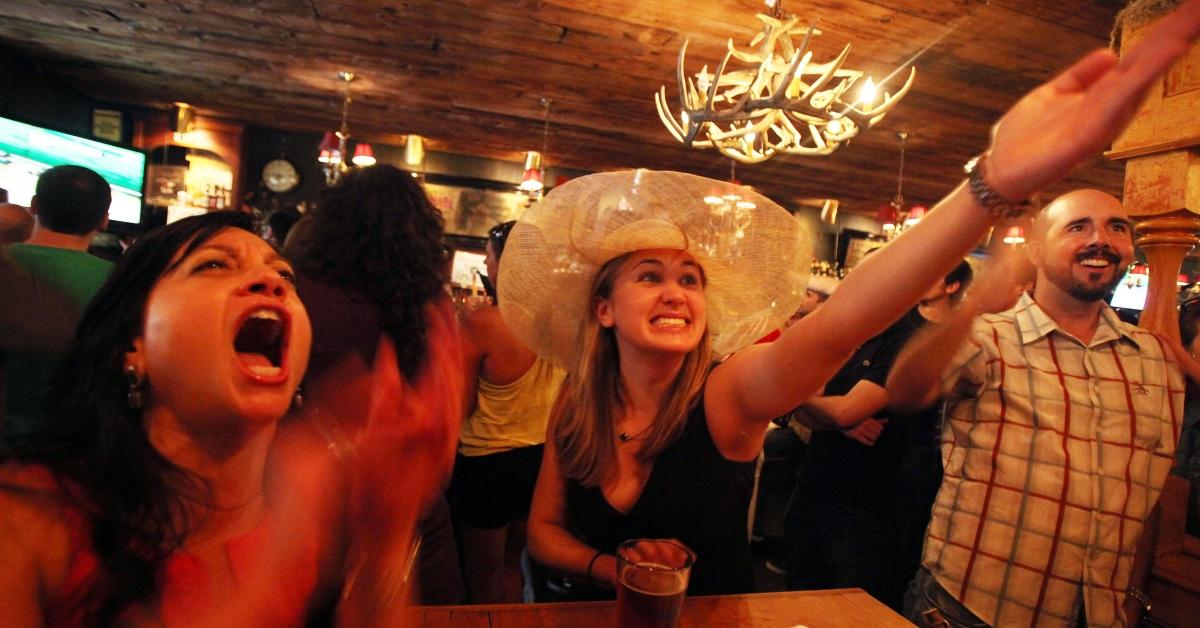 A woman in a hat watching the Kentucky Derby in a local bar. 