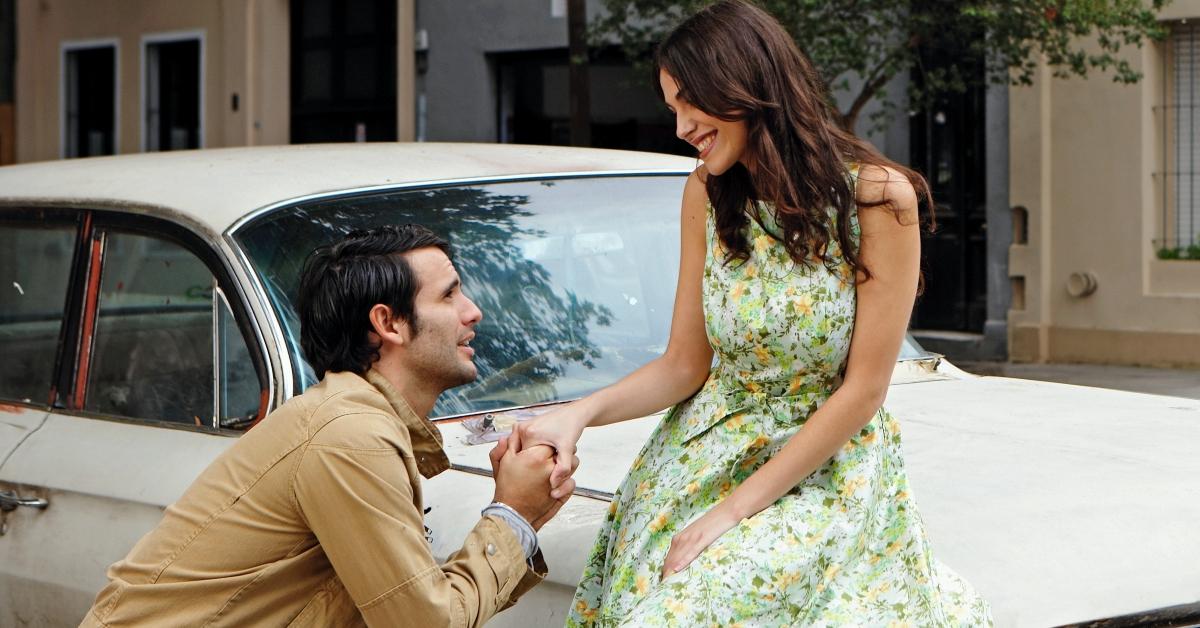 A couple showing affection on a car. 