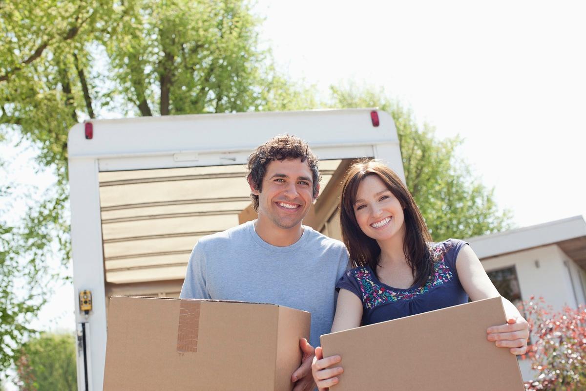 Couple unloading boxes from moving van 