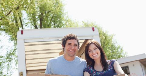 Couple unloading boxes from moving van