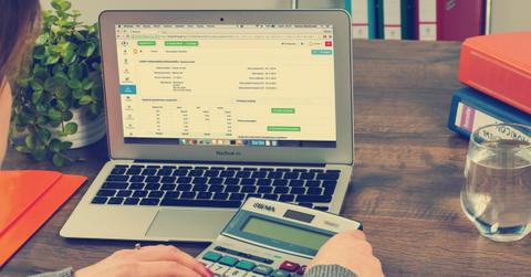 Person working on laptop and calculator