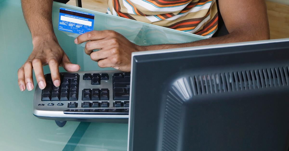 Young mans sits at computer with credit card