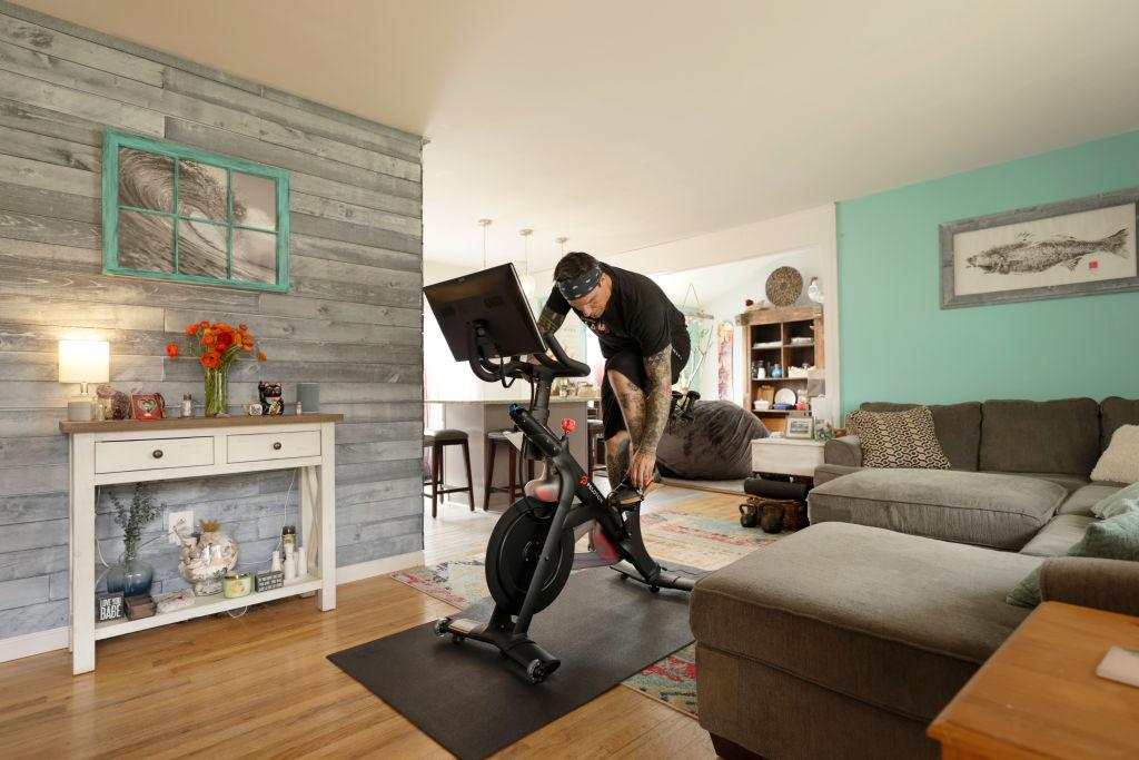 A man using a Peloton bike in his home