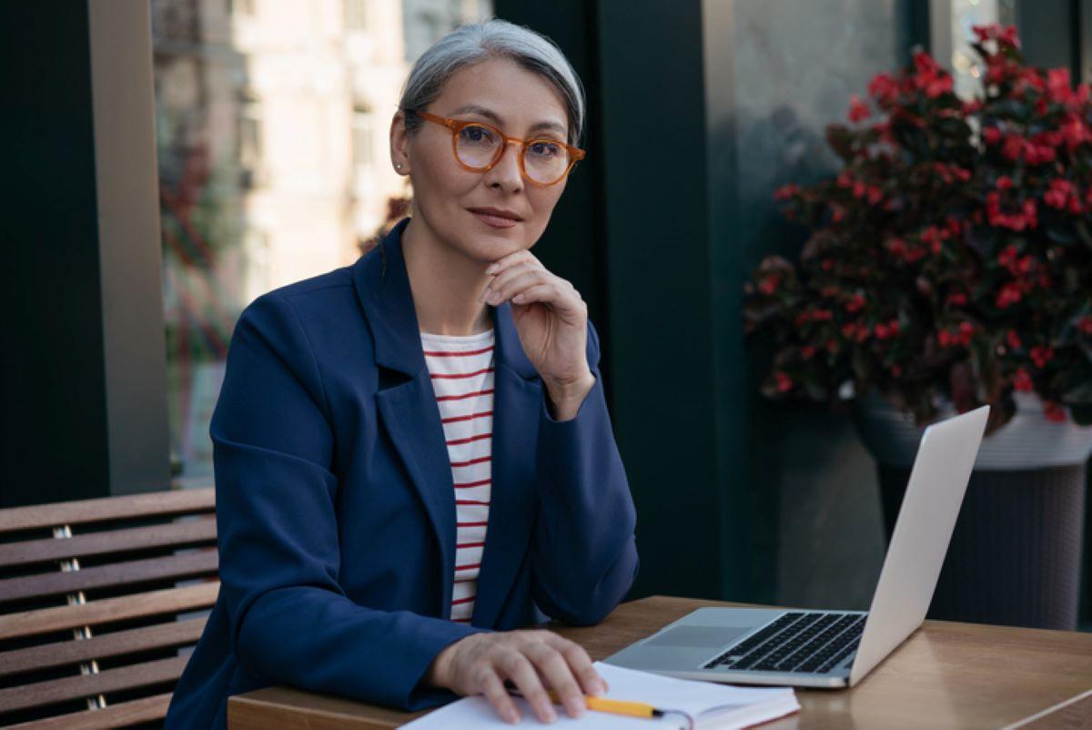 Woman with glasses looking up from her laptop