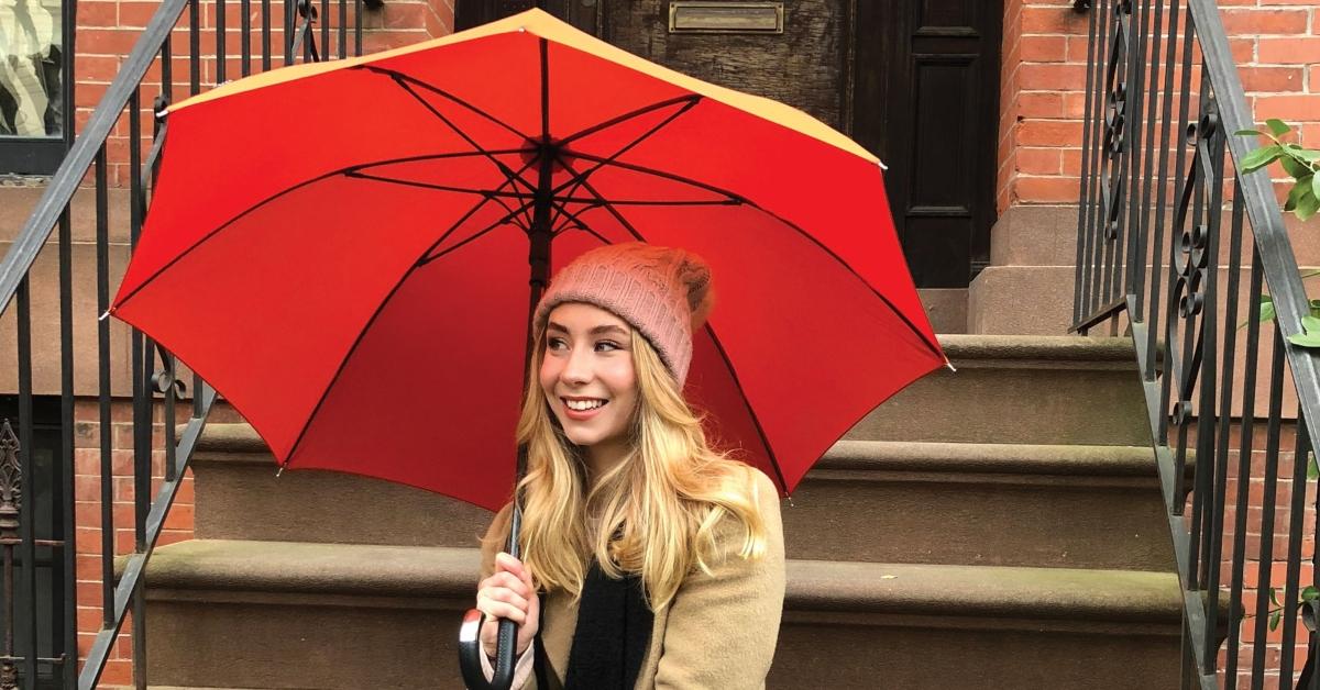 A woman smiling while holding an umbrella.