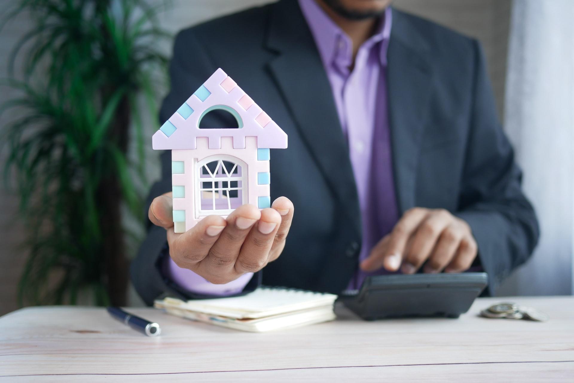 A person holding a miniature house in his hand