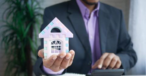 A person holding a miniature house in his hand