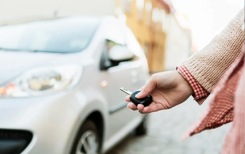  A person holding car keys in front of a car