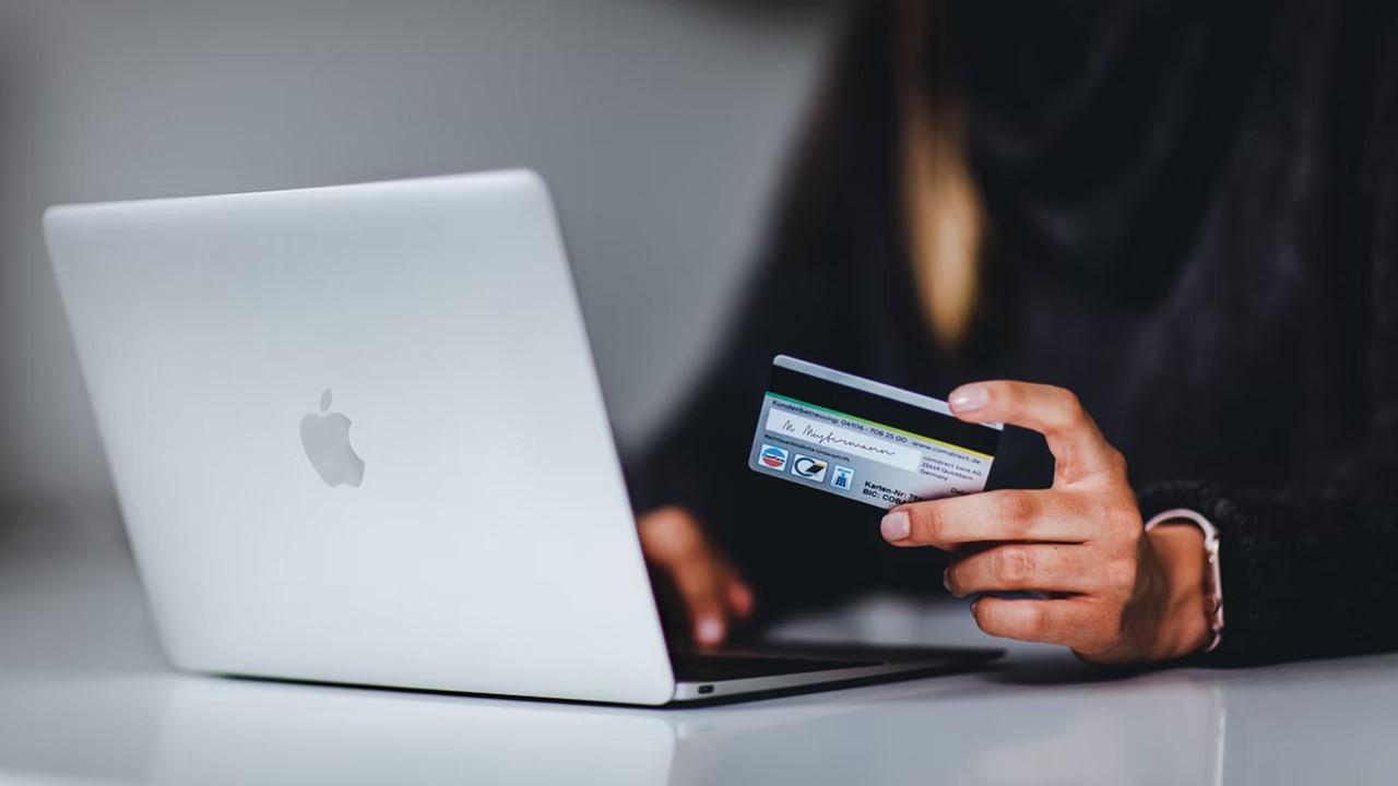 A person wearing a black top is making an online payment using their credit card.