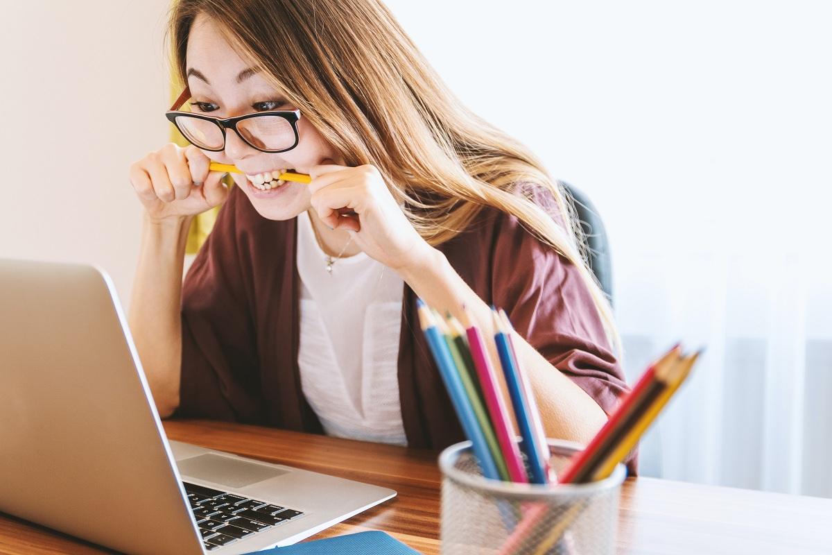 A student biting a pencil while working on a computer