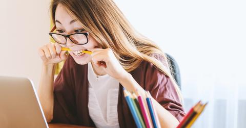 A student biting a pencil while working on a computer