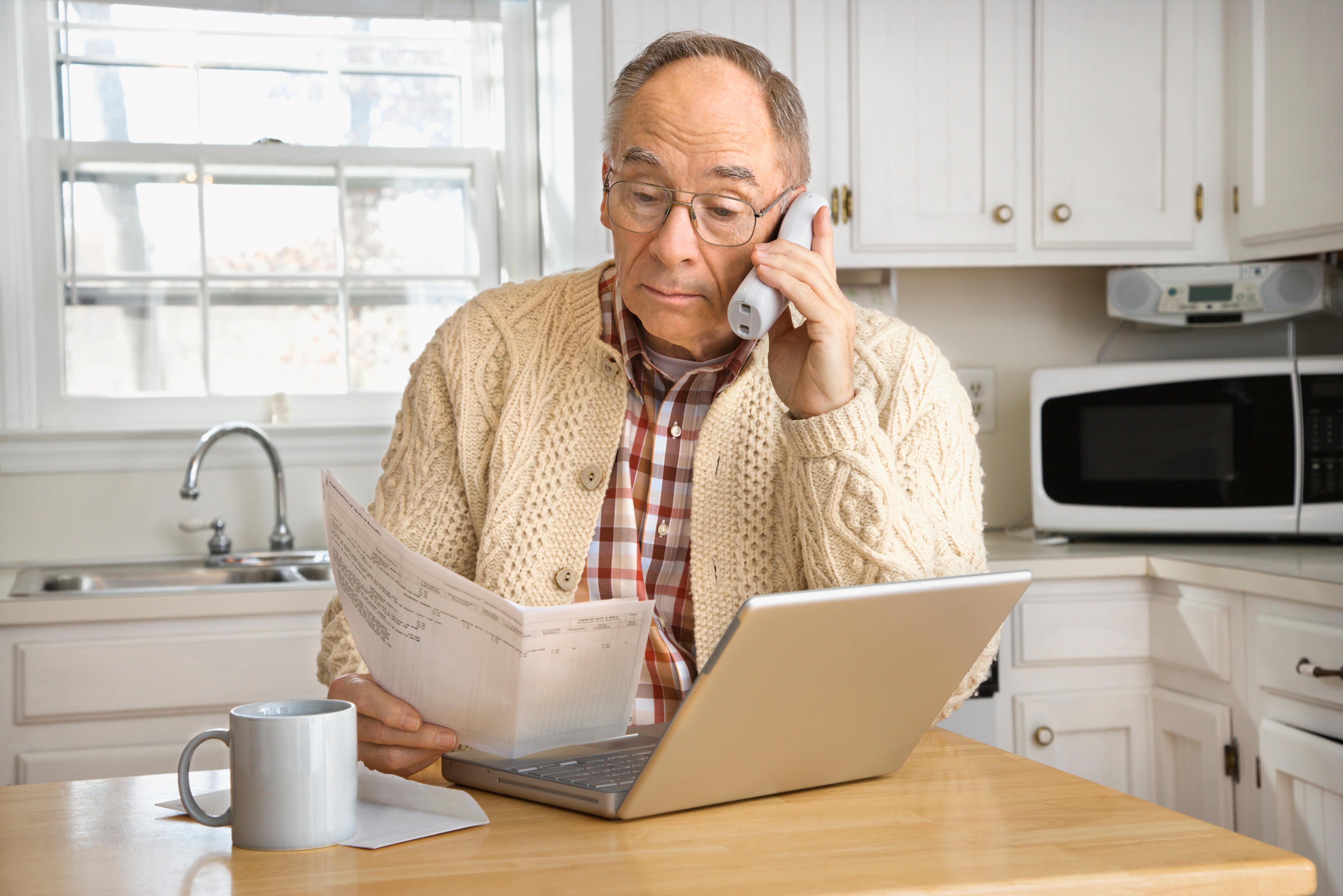 An elderly man uses the phone