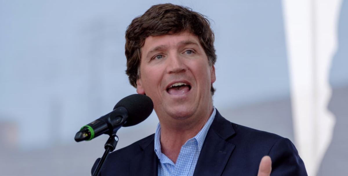 Carlson wearing a blue suit and speaking at the Mathias Corvinus Collegium (MCC) Feszt on Aug. 7, 2021