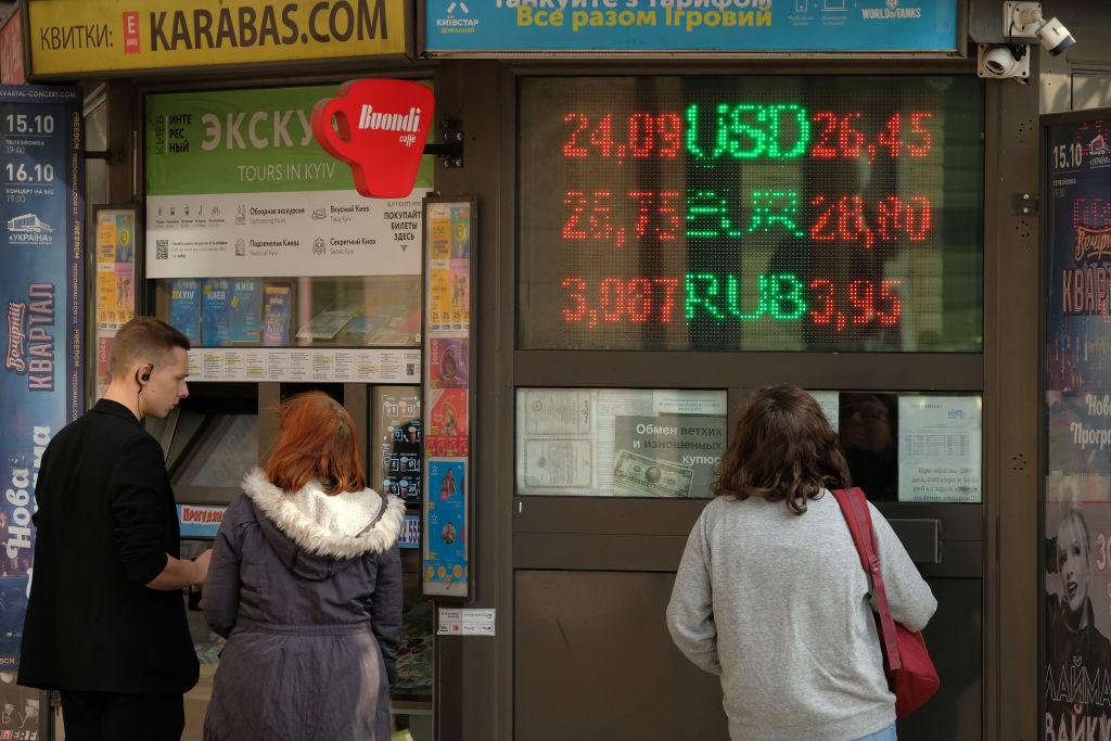 People looking at billboards with the Russian ruble's stock value