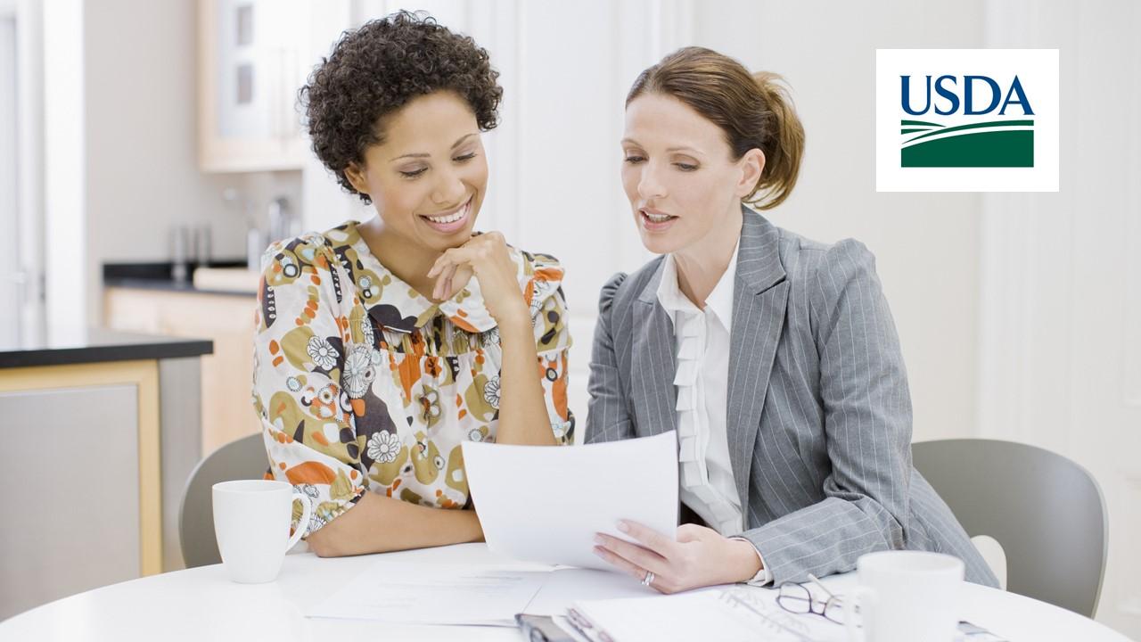 Two women discussing loans and USDA logo