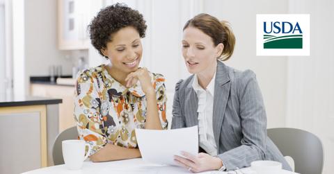 Two women discussing loans and USDA logo
