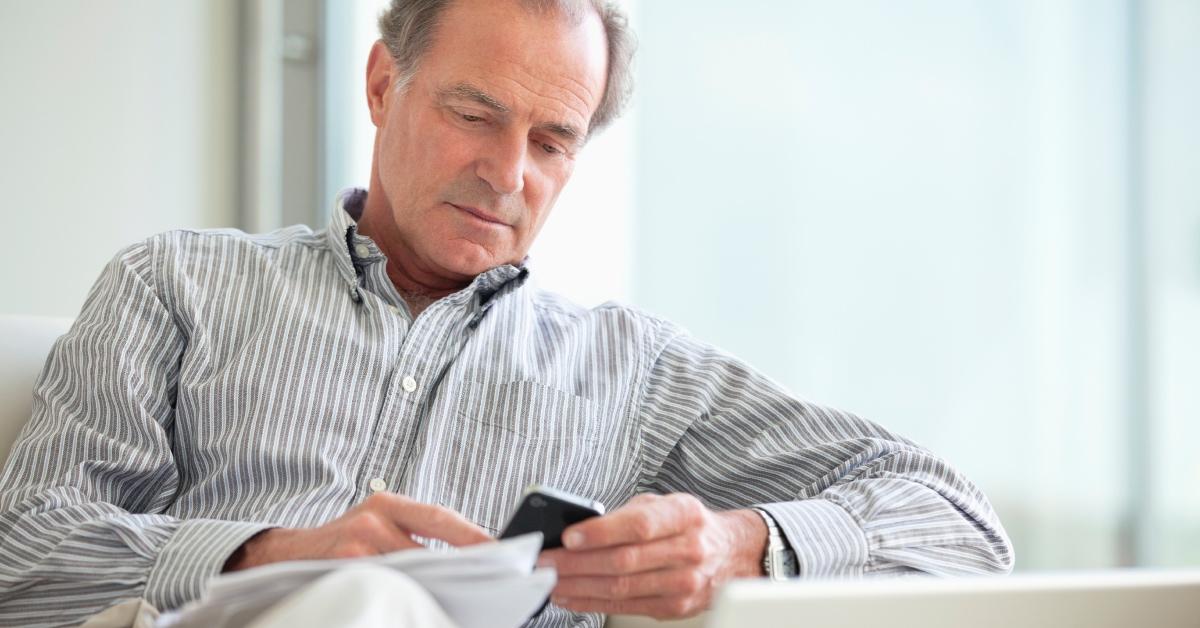 An elderly man checking his phone.