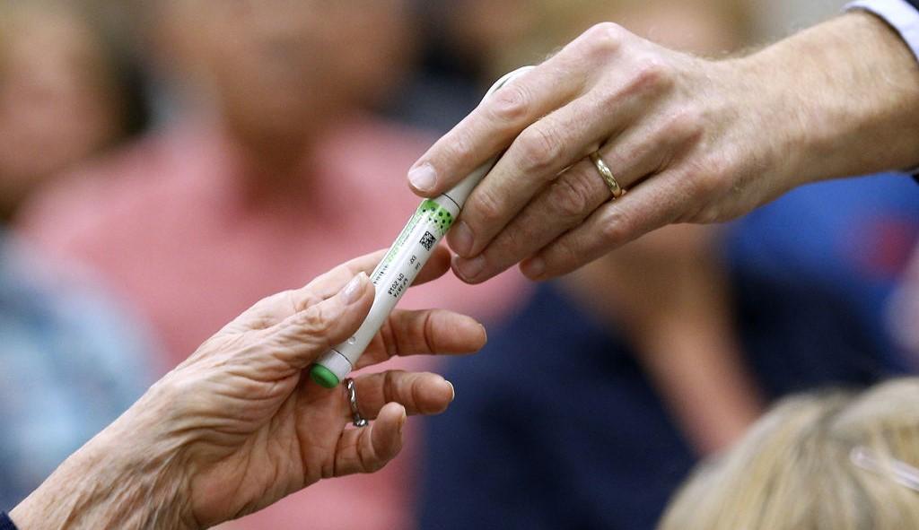 person handing someone a vial of insulin