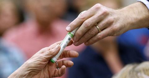 person handing someone a vial of insulin